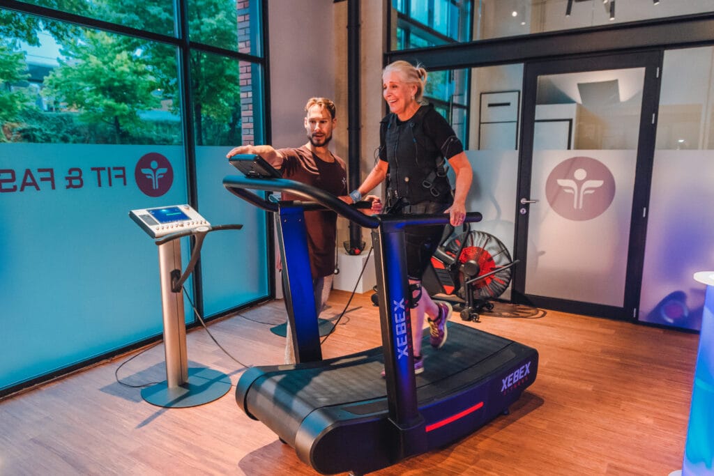 Een vrouw die met EMS cardio doet op de loopband samen met een trainer van Fit & Fast